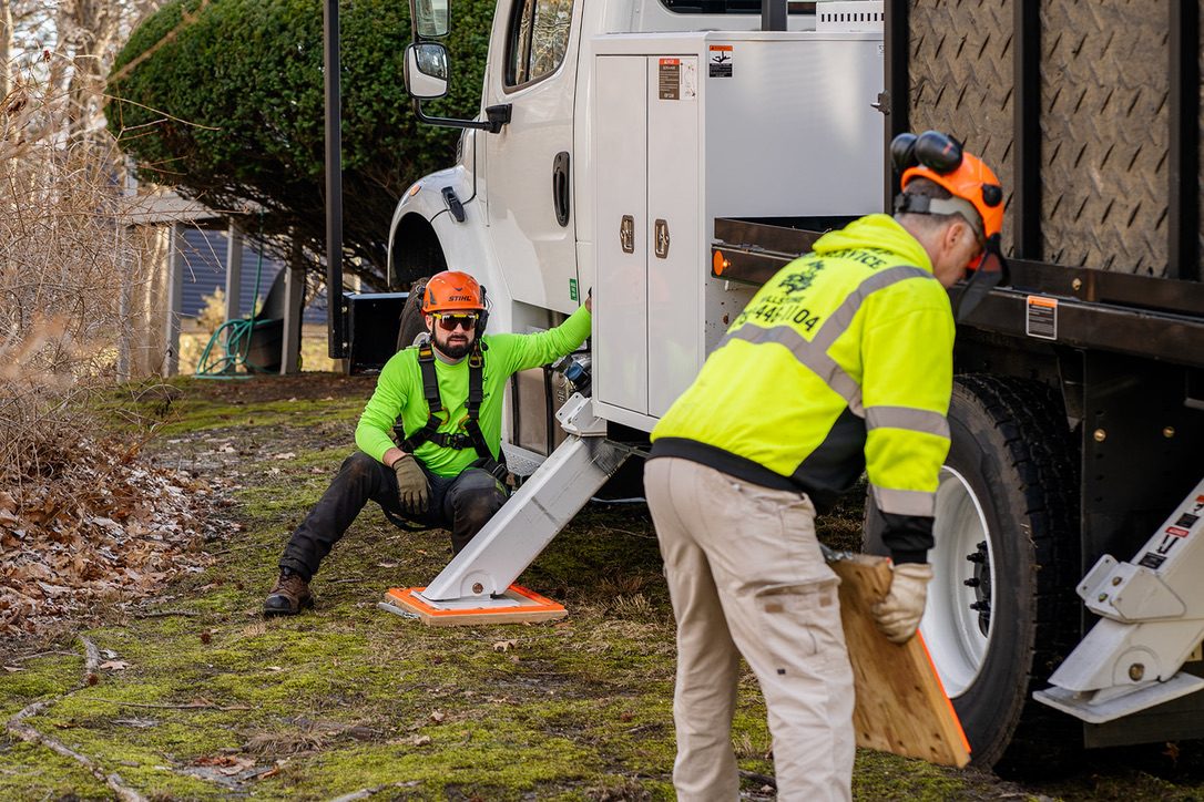 Pro-Stump crew stabilizing bucket truck outriggers before a residential job